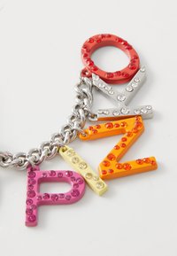 Farebná kľúčenka s akrylovými písmenami "O," "V," "Z," a "P," zdobená kamienkami, pripevnená k striebornému kovovému reťazcu.