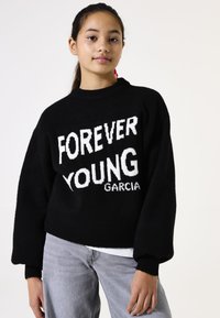 Jersey de punto negro con el destacado texto blanco "FOREVER YOUNG GARCIA". El diseño incluye un cuello y puños de canalé, con un corte holgado.