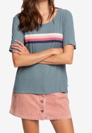 Lysblå kortærmet top med vandrette striber i pink, hvid og navy; parret med en pink fløjlsskjørt med knapdetaljer.