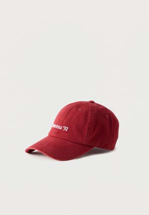 Casquette de baseball rouge à visière courbée avec un texte brodé blanc indiquant "Barcelona '92" à l'avant, présentée sur un fond clair uni.
