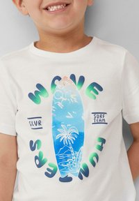 Weißes Baumwoll-T-Shirt mit einem blauen Surfbrett-Design und einer Palme, umgeben von dem Text "WAVE SURF TEAM" in grünen und blauen Farbtönen.