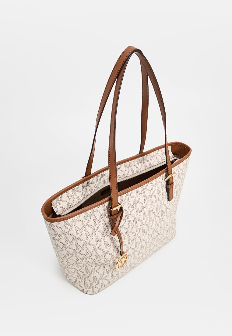 Sac fourre-tout avec un corps en toile crème, présentant un design à motifs, des poignées en cuir brun et un accent en métal doré.