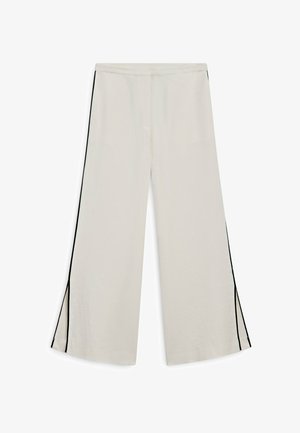 Weit geschnittene cremefarbene Hose mit schwarzen Seitenstreifen und kleinen Schlitzen am Saum, präsentiert vor weißem Hintergrund.