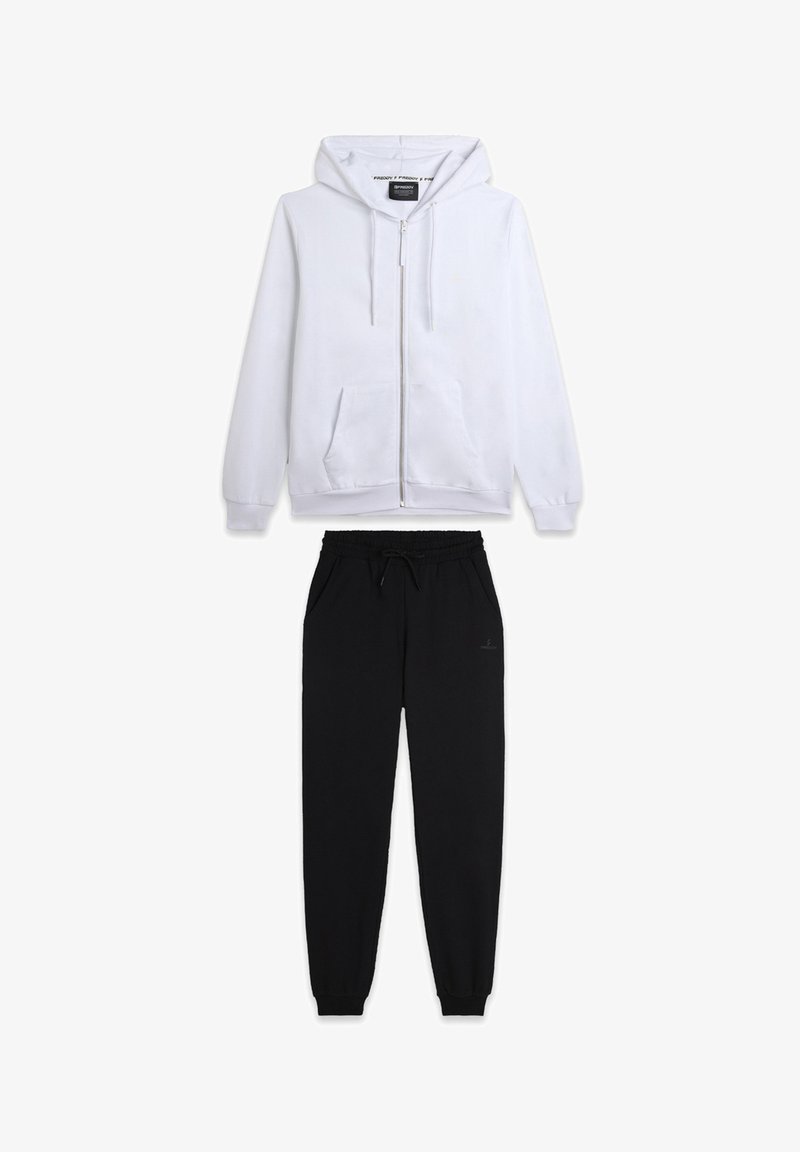 Sweatshirt à capuche zippé blanc avec poches avant, associé à un pantalon de survêtement noir à cordon de serrage avec une coupe ajustée.