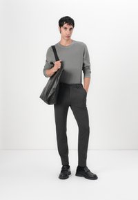 Graues Langarmhemd, dunkelgraue Slim-Fit-Hose, schwarze Schuhe und eine schwarze Ledertasche. Schlichte Linien, glatte Texturen.