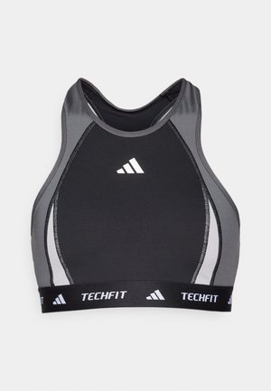 Svart sportsbh med grå detaljer, racerback-design og hvit "Techfit"-logo på båndet. Laget av elastisk, fukttransporterende materiale.