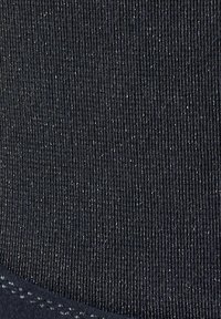 Schwarzer Stoff mit feiner gerippter Textur, der unten eine glatte Kante mit kontrastierender Nahtdetail aufweist.