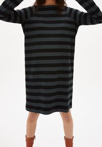 Černé a tmavě šedé pruhované šaty s volným střihem, kulatým výstřihem a dlouhými rukávy, sahajícími do poloviny stehna, vyrobené z měkké látky.