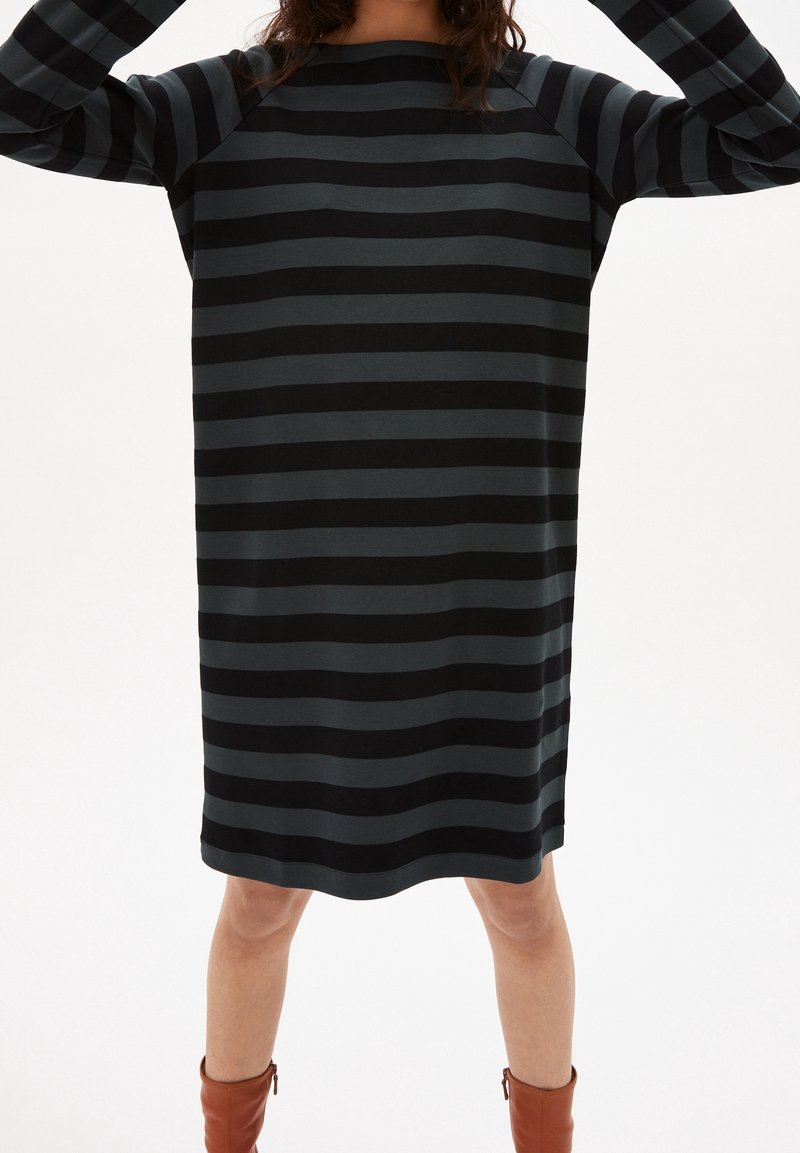 Černé a tmavě šedé pruhované šaty s volným střihem, kulatým výstřihem a dlouhými rukávy, sahajícími do poloviny stehna, vyrobené z měkké látky.