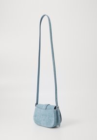 Borsa a tracolla in tessuto azzurro chiaro con una texture liscia, forma curvata e tracolla regolabile. Presenta una chiusura a bottone e un design minimalista.