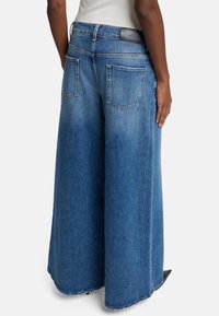 Breda jeans i blå denim med hög midja, bakfickor, en icke-sliten finish och en rå fåll i botten.
