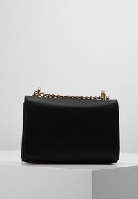 Borsa in pelle nera di forma rettangolare, dotata di una tracolla in catena dorata e dalla superficie liscia. Design minimalista senza ulteriori motivi.