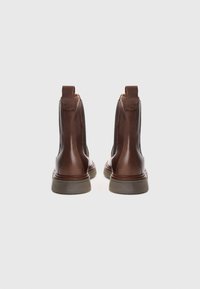 Bottines en cuir marron avec des panneaux élastiques sur les côtés, bouts ronds, semelles en caoutchouc plates et languettes en boucle à l'arrière.