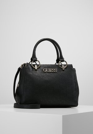 Czarna torebka Guess z wytłaczanym wzorem logo w kształcie okręgów, dwoma okrągłymi uchwytami, srebrnymi metalowymi pierścieniami oraz odpinanym paskiem na ramię na białej powierzchni.