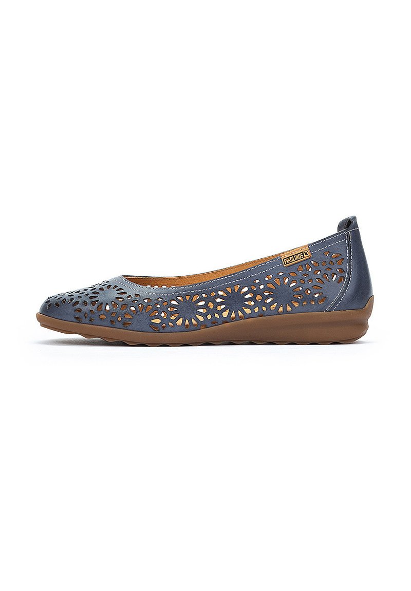 Bailarinas de cuero azul con diseño floral troquelado, suela de goma marrón y interior de cuero marrón. Presentan un perfil bajo y un estilo fácil de poner.