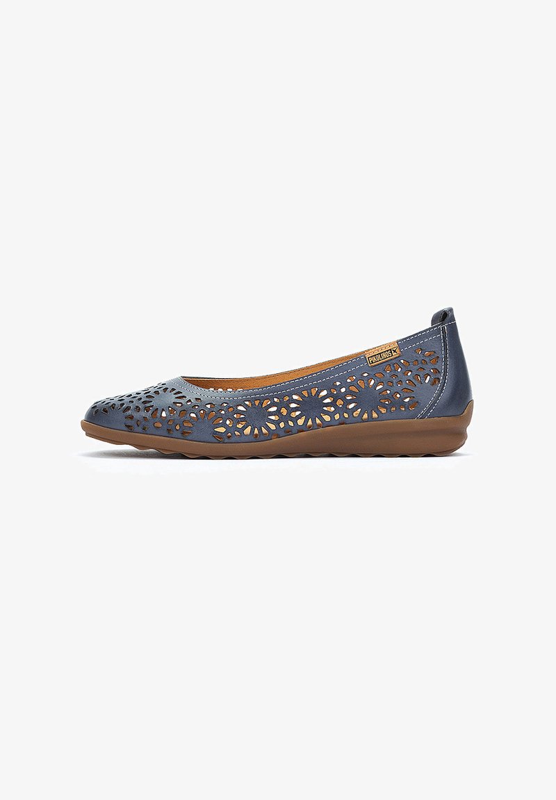 Bailarinas de cuero azul con diseño floral troquelado, suela de goma marrón y interior de cuero marrón. Presentan un perfil bajo y un estilo fácil de poner.