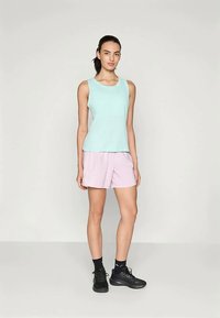 Licht turquoise mouwloos topje gecombineerd met zachte roze shorts. De outfit heeft een relaxte pasvorm en wordt aangevuld met zwarte sportschoenen.