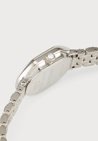Edelstahl-Uhr mit einem polierten silbernen Gehäuse, runder Form und mit Kristallen verziertem Krone. Verfügt über ein Metallarmband.
