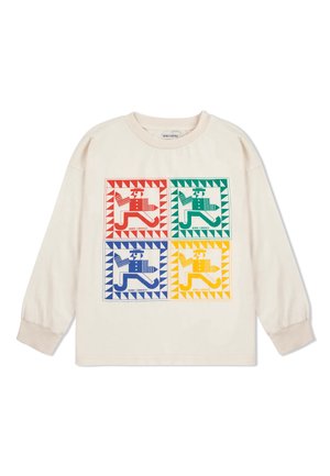 Chemise beige clair à manches longues présentant quatre carrés graphiques colorés avec des figures de chien stylisées en rouge, vert, bleu et jaune. Texture douce.