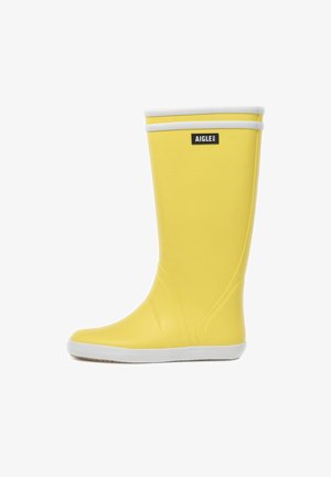 Botte de pluie en caoutchouc jaune avec une surface lisse, une bande d'accent blanche en haut et une semelle texturée pour l'adhérence. Logo de la marque affiché.