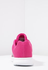 Zapatilla deportiva de malla rosa con un tacón redondeado, suela de goma blanca y un collar acolchado. Etiqueta interior visible cerca de la abertura.