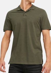 Polo shirt verde oliva in cotone. Presenta un colletto classico, maniche corte e un piccolo logo sul lato sinistro del petto. Design semplice.