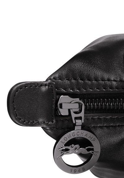 Schwarze Lederhülle mit Reißverschluss, ausgestattet mit einem silberfarbigen Hardware-Zipper und einem runden Anhänger mit einem Pferdelogo sowie der Gravur "LONGCHAMP 1948".