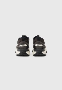 Dark gray athletic shoes with a textured upper, contrasting white midsole, and black rubber outsole. Features a pull tab at the heel.
