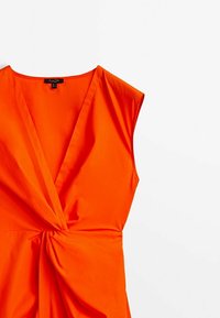 Robe orange vif en tissu lisse. Présente un décolleté en V profond, des manches courtes et un détail noué torsadé à la taille.