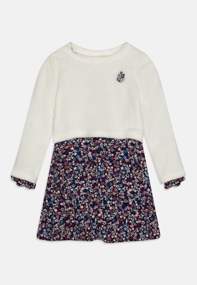 Robe enfant à manches longues avec un haut blanc comportant un petit blason et une jupe à motif floral multicolore en bleu marine, rouge et blanc.