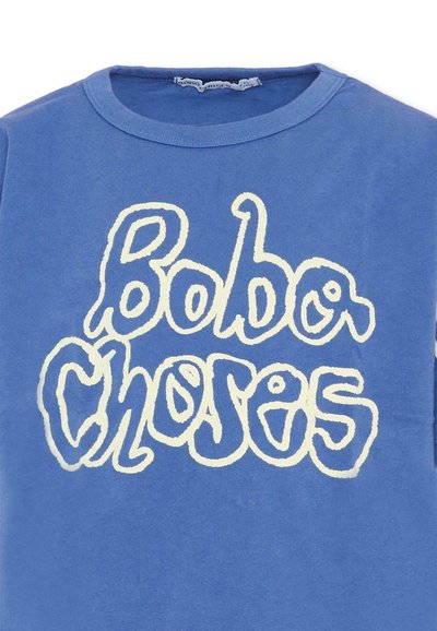 T-shirt bleu à col rond avec un texte stylisé blanc "Bobo Choses" sur la poitrine, écrit dans une police ludique et irrégulière.