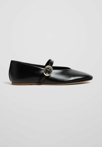 Ballerine in pelle nera con punta affusolata, caratterizzate da una cintura decorativa e dettagli in metallo a forma di fibbia. Texture liscia e suola piatta.
