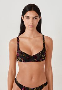 Zwarte bh met bloemmotief in paars, rood en goud, met kantafwerking en verstelbare bandjes, gecombineerd met bijpassende bikinitopjes.