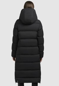 Abrigo negro acolchado con capucha, que presenta secciones de acolchado horizontal, un diseño hasta la rodilla y bolsillos con cremallera a los lados.