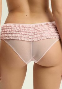 Różowe siateczkowe majtki z falbaną w pasie, posiadające warstwowe falbany. Materiał wydaje się miękki i przezroczysty, podkreślając delikatny design.