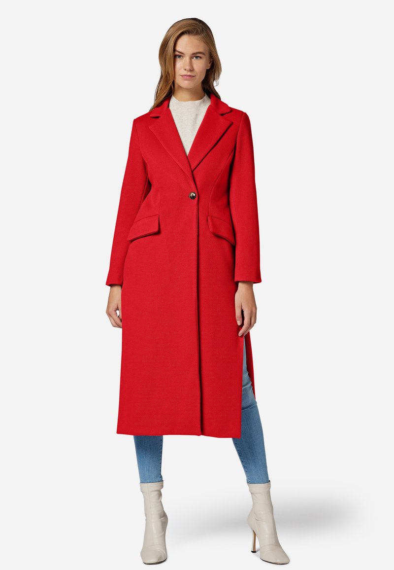 Manteau long rouge avec un design structuré, présentant un col à revers, deux poches avant et une fermeture à un bouton. Texture lisse.
