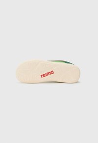 Suela de zapatilla verde y negra con goma blanca texturizada y un prominente logotipo rojo "reima", diseñada para tracción y durabilidad.