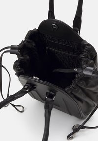 Sac seau en cuir noir avec fermeture à cordon, doubles poignées, rabat magnétique et poche intérieure zippée avec doublure à motif.