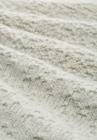 Tissu tricoté gris clair avec un motif texturé, présentant des stries surélevées et une finition douce et duveteuse. Des vagues lisses créent une apparence en couches.