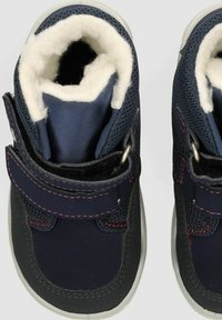 Botas infantiles de color azul marino con suave forro blanco, correa de velcro, detalles en malla y suelas de goma gris, que presentan costuras en rosa contrastante.