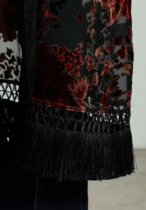 Sopa de flores negras con superposición transparente, adornada con flores de terciopelo rojas y burdeos, que presenta flecos negros y un elaborado encaje en el dobladillo.