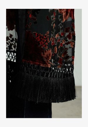 Zwarte doorzichtige sjaal met rode en bordeaux florale velours patronen, omzoomd met een zwarte franjestrim en ingewikkelde haakdetails.