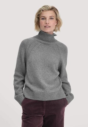 Grauer Strickpullover mit hohem Kragen, gerippten Bündchen und Saum. Verfügt über Raglanärmel und eine weiche Textur, kombiniert mit dunklen Cordhosen.