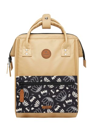 Sac à dos beige avec une surface texturée, deux poignées supérieures, et une poche avant à motif floral noir. Présente une fermeture éclair et un patch logo.