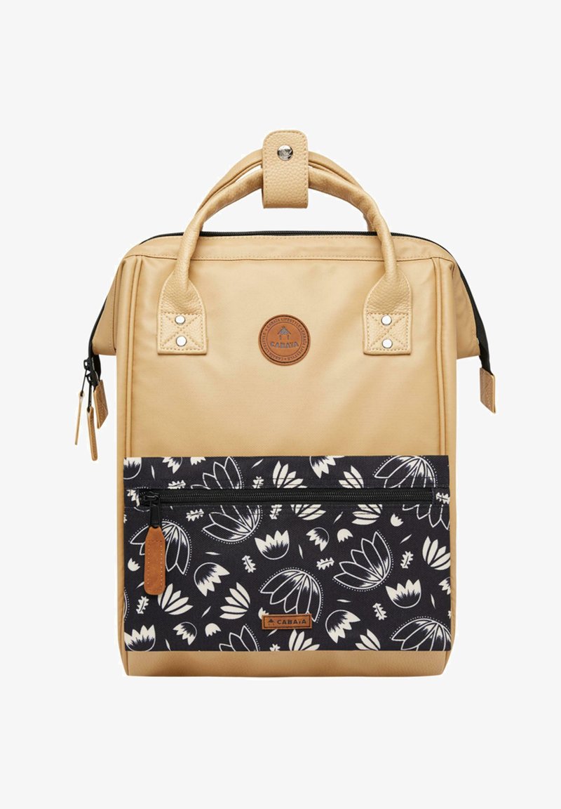 Sac à dos beige avec une surface texturée, deux poignées supérieures, et une poche avant à motif floral noir. Présente une fermeture éclair et un patch logo.