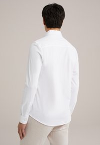 Hvid langærmet skjorte med spidse kraver og knapmanchetter, lavet af glat stof, med en lige rygdesign.
