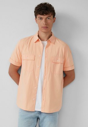 Korte mouwen, button-up shirt in pastel perzik met een gestructureerde afwerking, voorzien van twee borstzakken en opgerolde mouwen. Draag het over een wit T-shirt.