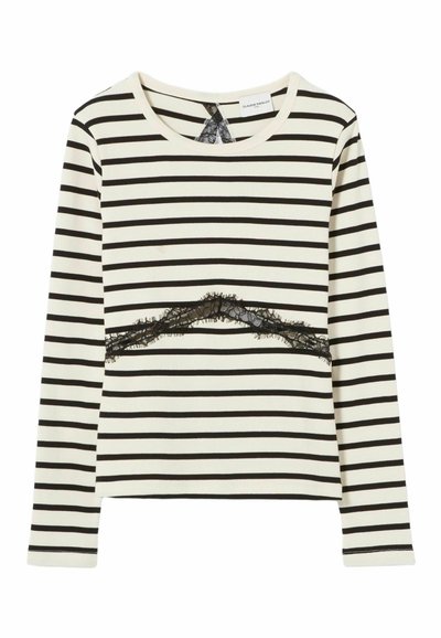Top de manga larga en color crema con rayas horizontales negras, que presenta un detalle de encaje negro en el pecho y un escote redondo.
