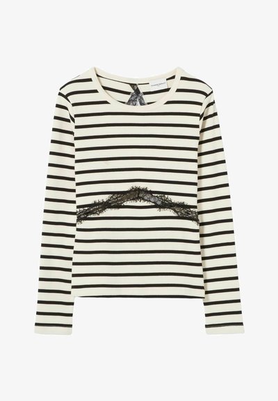 Top de manga larga en color crema con rayas horizontales negras, que presenta un detalle de encaje negro en el pecho y un escote redondo.