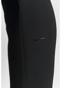 Leggings neri realizzati in un materiale elasticizzato, con un sottile logo Nike nero sulla coscia, texture liscia e design aderente.
